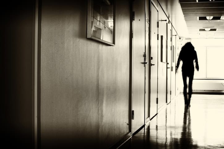 Person walking down a hallway toward light