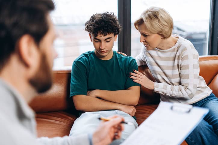 Mother supporting her teenage son during a juvenile legal consultation